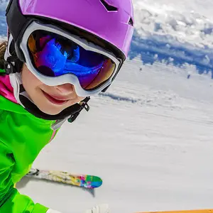 Criança com roupa verde esquiando.