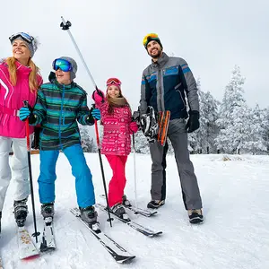 Família com roupa e equipamentos de esqui.