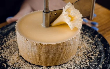 Queijo tête de moine sendo fatiado.