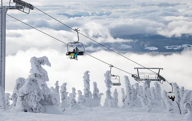 teleférico passando por cima de arvores congeladas em montanha com neve