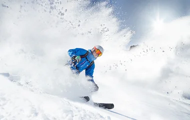 Homem esquiando e levantando a neve powder.