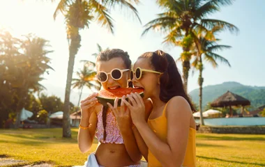 duas meninas de óculos de sol comendo melancia
