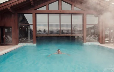 Homem nadando em piscina aquecida nos Alpes