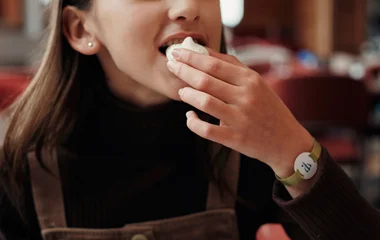 Menina comendo um cheesecake de frutas vermelhas.