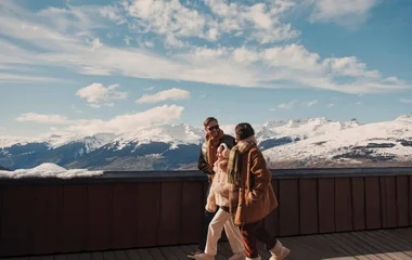 Família caminhando pelo resort, com montanhas cobertas de neve como pano de fundo