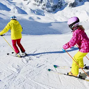 Homem e mulher esquiando com roupas rosas e amarelas.