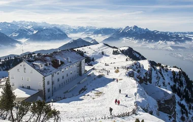 Montanha Rigi em dia de sol com visitantes no topo.