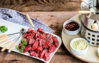 prato de carnes ao lado de aquecedor com molhos em volta