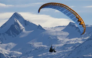 Pessoa saltando de parapente nos alpes.