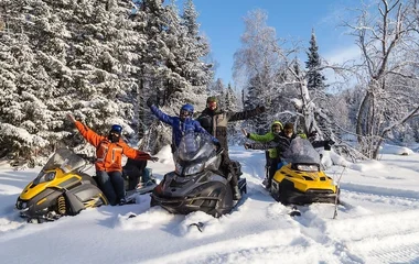 Três pessoas andando de snowmobile.