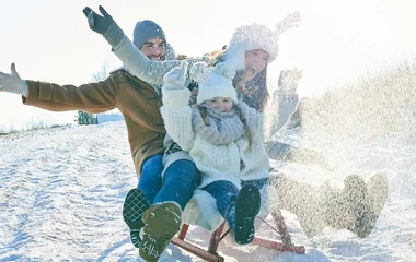 Família descendo de trenó na neve.