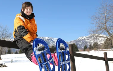 Criança com raquete para caminhada na neve.