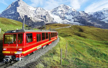 Trem passando pelas montanhas durante o dia.