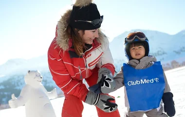 Criança ao lado da instrutora em aula de esqui.