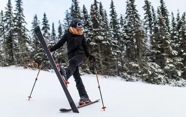 Mulher com roupa e equipamento de esqui na neve.