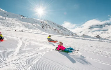 Pessoas descendo em trenó de neve em Tignes.