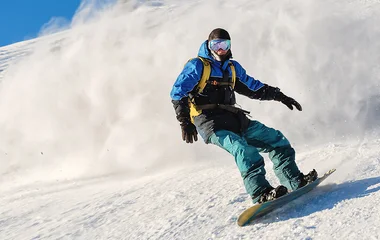 Homem de azul praticando snowboard.