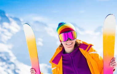 Mulher sorrindo enquanto segura os equipamentos de esqui.