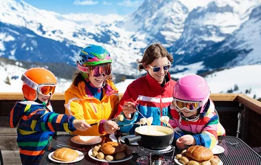 Família comendo com a paisagem dos alpes ao fundo.