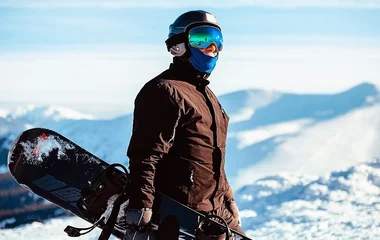 Homem com esquipamento de snowboard na neve