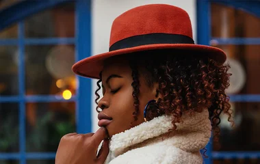 Mulher com casaco de pelo sintético e chapéu.