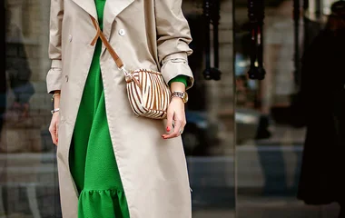 Mulher de vestido verde e casaco cáqui.
