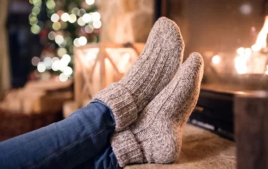 Mulher usando meias em frente a uma lareira.