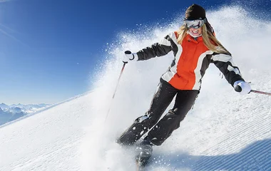 Mulher esquiando com roupa preta, branca e vermelha.