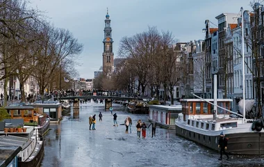 Pessoas passeando por Amsterdã em dia de neve.