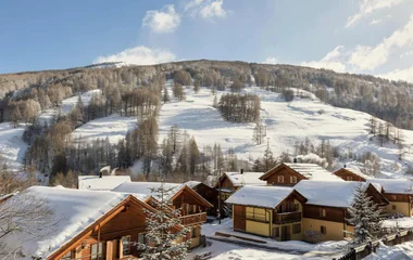 Vista aérea de las villas del Club Med Pragelatto durante el día, con los techos cubiertos de nieve.