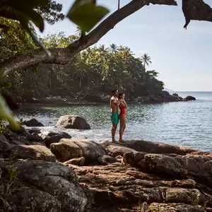 casal abraçados em cima de uma rocha na praia