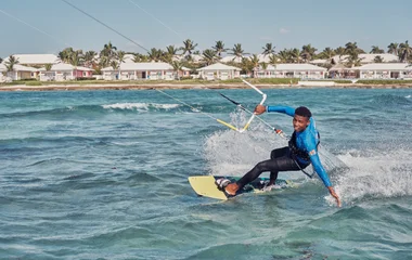 praticante de kitesurf voando sobre o mar