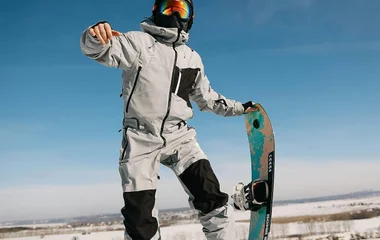 Homem saltando com a prancha de snowboard.