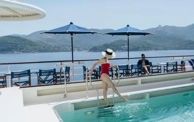 Mulher de maio vermelho e chapéu em piscina.
