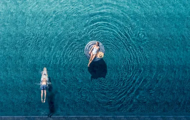 mulher em boia e homem mergulhando em piscina