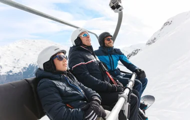 Três pessoas no teleférico da estação de esqui.