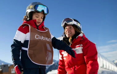 Criança ao lado de monitora do Club Med.