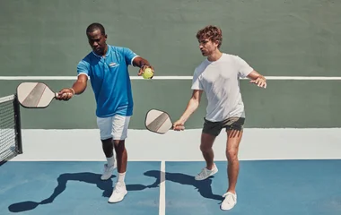 Dois homens praticando saque com a raquete de tênis.