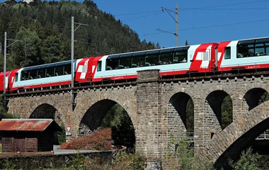 trem vermelho sobre trilhos em construção de pedras