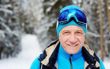 Homem com o óculos de neve sobre touca na cabeça.
