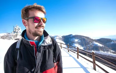 Homem de óculos em paisagem de neve.