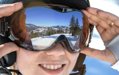 Mulher segurando os óculos de neve.