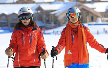 Duas mulheres com roupas e equipamentos de esqui.