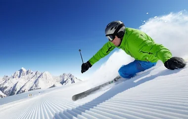 Homem esquiando com roupa verde e azul.