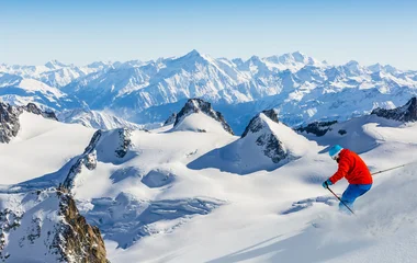 Homem esquiando com roupa laranja e azul.