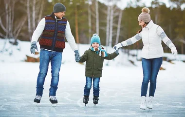 Pai, mãe e filho patinando no gelo.