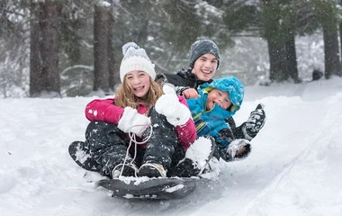 Três crianças num trenó de neve.