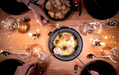 Pessoas comendo fondue de queijo.