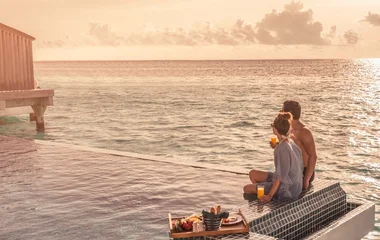 Finolhu, Maldives - Couple having breakfast by the pool at overwater villa