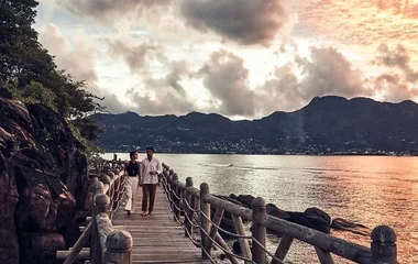 A honeymoon couple walks at sunset at a luxury beach resort